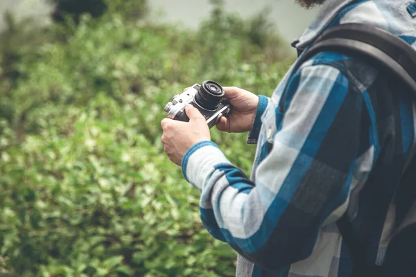 Vintage film camera in the hands of a man on a blurred background, the concept of tourism and camping, copy space.