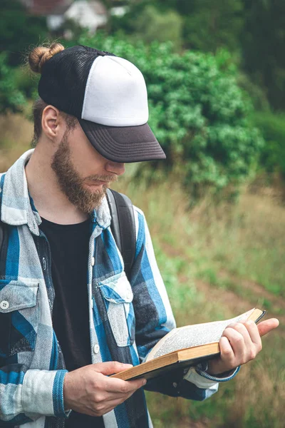 Man Plaid Shirt Cap Reads Book Nature — Stok fotoğraf