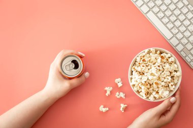Popcorn, keyboard and drink in female hands, flat lay, concept of watching movies and series.