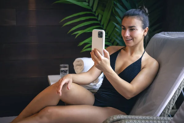 Young Woman Swimsuit Relaxing Spa Complex Using Smartphone — Stockfoto