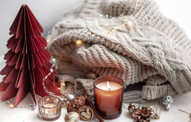 Yanan mumlarla, örülmüş elementlerle ve dekoratif detaylarla sıcak kış kompozisyonu.