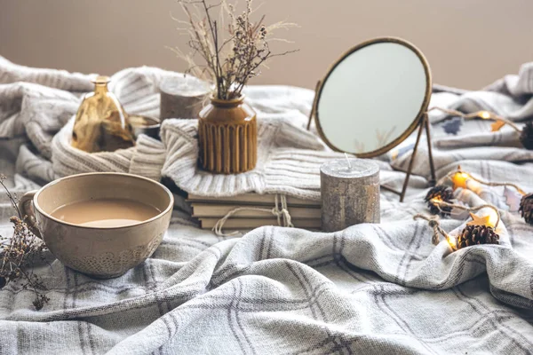 Cozy autumn composition with a cup of coffee, a mirror and candles in the bed.