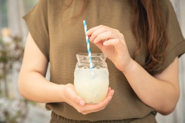 Close-up, a glass of cooling lemonade in female hands.