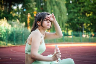 A young woman with a bottle of water in training at the stadium.