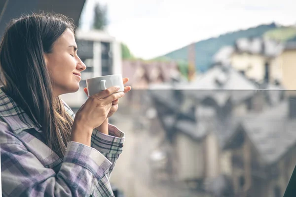 A woman drinking coffee on the balcony in the morning, copy space.