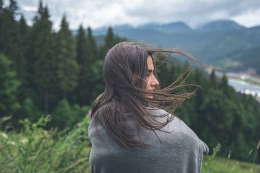 Dağlarda ekoseye sarılı genç bir kadın bulanık bir arkaplanda, boşluğu kopyala.