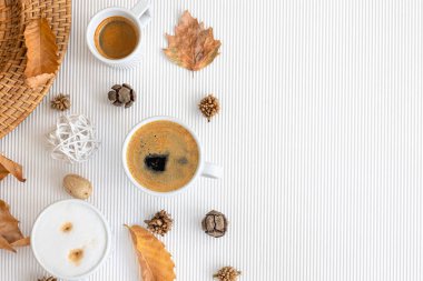 Autumn composition with cups of coffee and leaves on a textural white background, flat lay, copy space.