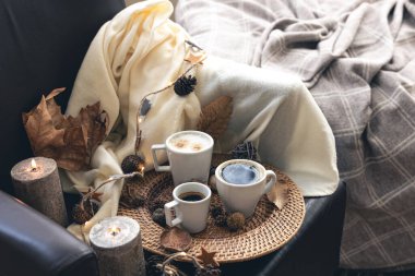 Cozy home composition with coffee cups, leaves and a plaid.