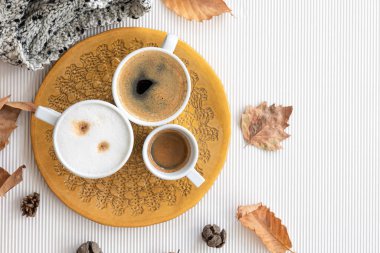 Autumn composition with cups of coffee and leaves on a textural white background, flat lay, copy space.