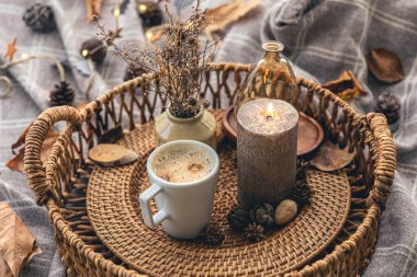 Cozy home composition with a cup of coffee, a candle and decorative details, close up.