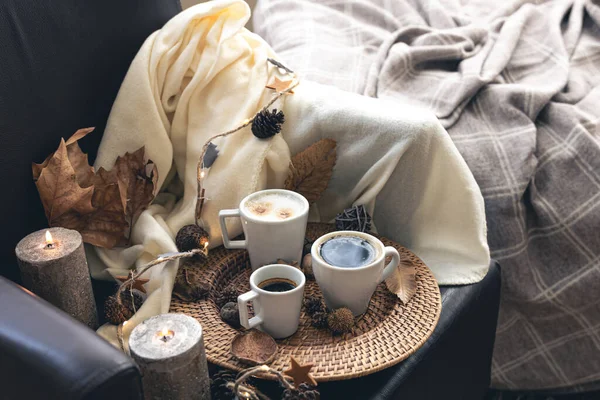 Cozy home composition with coffee cups, leaves and a plaid.