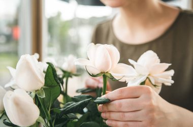 Close-up, a bouquet of delicate white roses in the hands of a female florist.