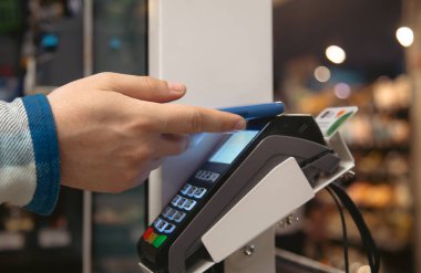 Close up of male hand holding smartphone in payment terminal, Paypass technology concept.