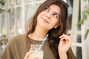 Attractive young woman with a glass of cooling lemonade on a hot summer day.