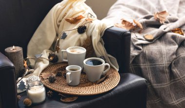 Cozy home composition with coffee cups, leaves and a plaid.