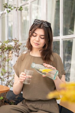 Attractive young woman drinking water with lemon, water balance concept.