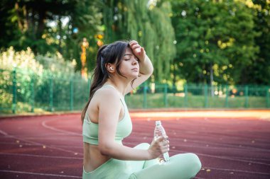 A young woman with a bottle of water in training at the stadium.