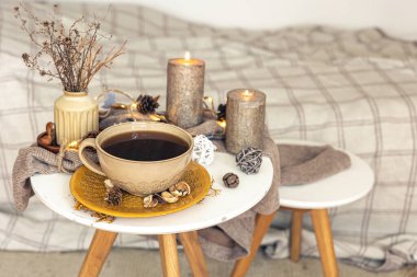 Cozy autumn composition with a cup of tea, candles and decorative details on a blurred background, copy space.