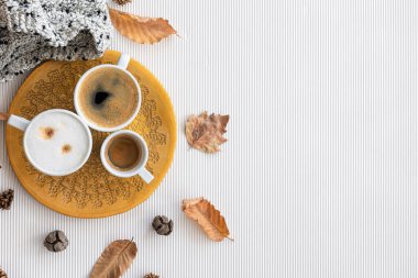 Autumn composition with cups of coffee and leaves on a textural white background, flat lay, copy space.
