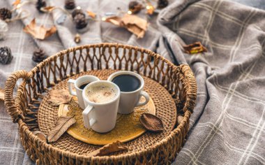 Cozy home composition with coffee cups, leaves and a plaid.