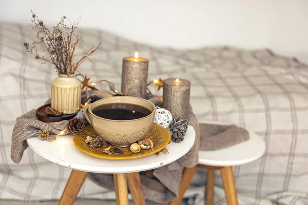 Cozy autumn composition with a cup of tea, candles and decorative details on a blurred background, copy space.