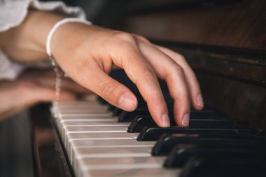 Female hands play on an old wooden piano, close-up.