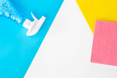 Boş temizlik spreyi şişesi ve beyaz arka planda renkli paçavralar. Düz yerde, üst tarafta. Ev temizliği ve temizlik konsepti.