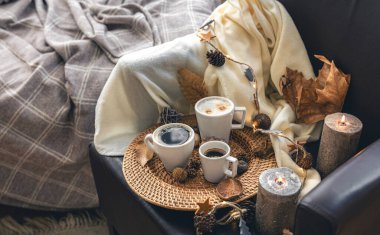 Cozy home composition with coffee cups, leaves and a plaid.
