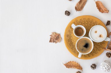 Autumn composition with cups of coffee and leaves on a textural white background, flat lay, copy space.