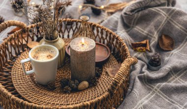 Cozy home composition with a cup of coffee, a candle and decorative details, close up.