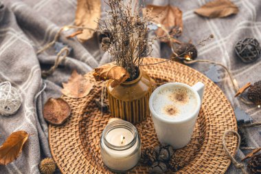 Cozy home composition with a cup of coffee, a candle and decorative details, close up.