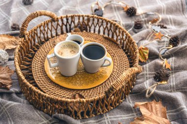 Cozy home composition with coffee cups, leaves and a plaid.