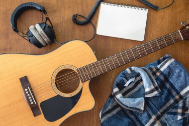 Music background with guitar, headphones and notepad, top view, musical creativity concept.