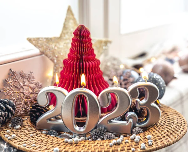Christmas background with decorative candles 2023 and decor details on a blurred background.