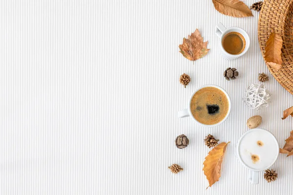 Autumn composition with cups of coffee and leaves on a textural white background, flat lay, copy space.