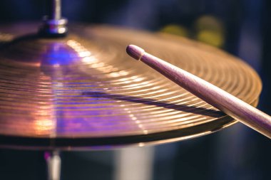 Hi-hat close-up of plates with drumsticks on a background of colored lanterns. Musical concept with a working drum.