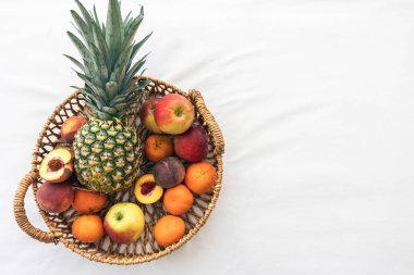Ananas ve diğer egzotik meyveler sepetin içinde beyaz arka planda, üst görünümde, boşluğu kopyala.
