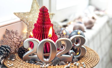 Christmas background with decorative candles 2023 and decor details on a blurred background.