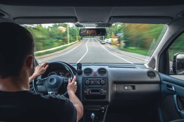 A male driver drives at speed through the streets of the city, a view from inside the car.