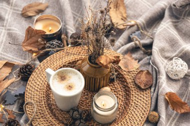 Cozy home composition with a cup of coffee, a candle and decorative details, close up.