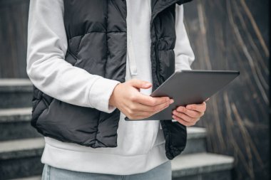 Kapatın, kadın tablet kullanıyor, şehir arka planı bulanık, vücut parçası.