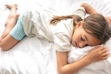 Pijamalı şirin bir kız yatakta tatlı tatlı uyuyor..