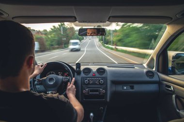 A male driver drives at speed through the streets of the city, a view from inside the car.