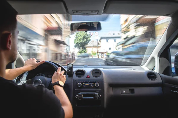 A male driver drives at speed through the streets of the city, a view from inside the car.