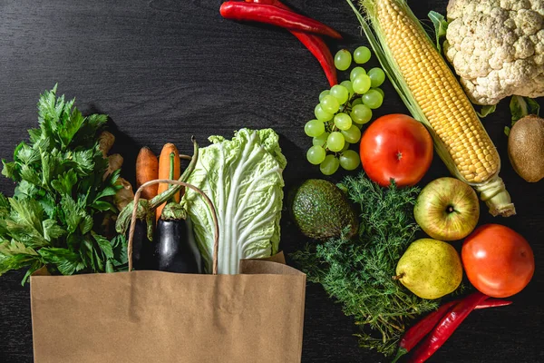 Flat lay, vegetables, fruits and package on black background.