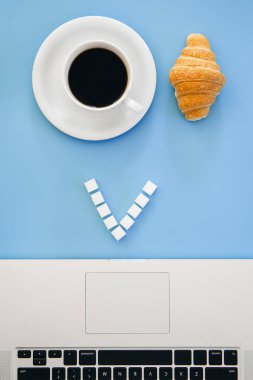 Ay çöreği, kahve fincanı ve dizüstü bilgisayar mavi arka planda, düz uzanma, kavramsal minimalizm.