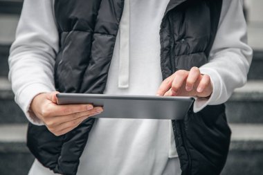 Kapatın, kadın tablet kullanıyor, şehir arka planı bulanık, vücut parçası.