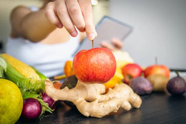 Close-up, an apple in a womans hand, among vegetables and fruits, the concept of cooking.