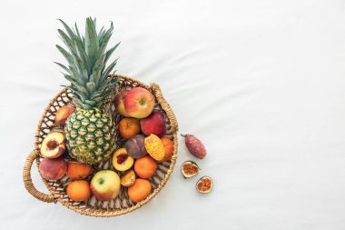 Ananas ve diğer egzotik meyveler sepetin içinde beyaz arka planda, üst görünümde, boşluğu kopyala.