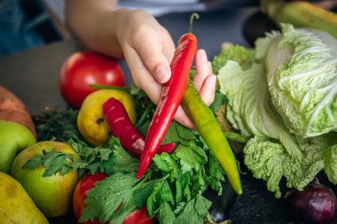 Sebzelerin arka planında kadın ellerinde acı biber, yemek pişirme kavramı..